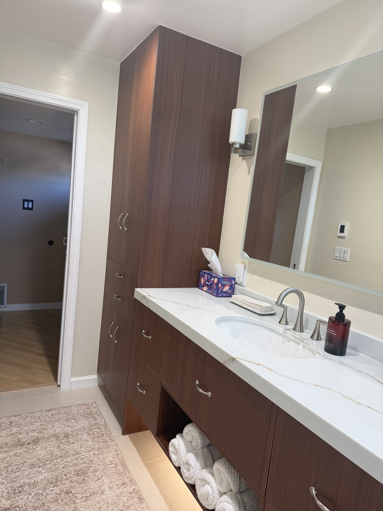 SSF tall walnut storage tower beside the vanity with drawers and a white quartz countertop