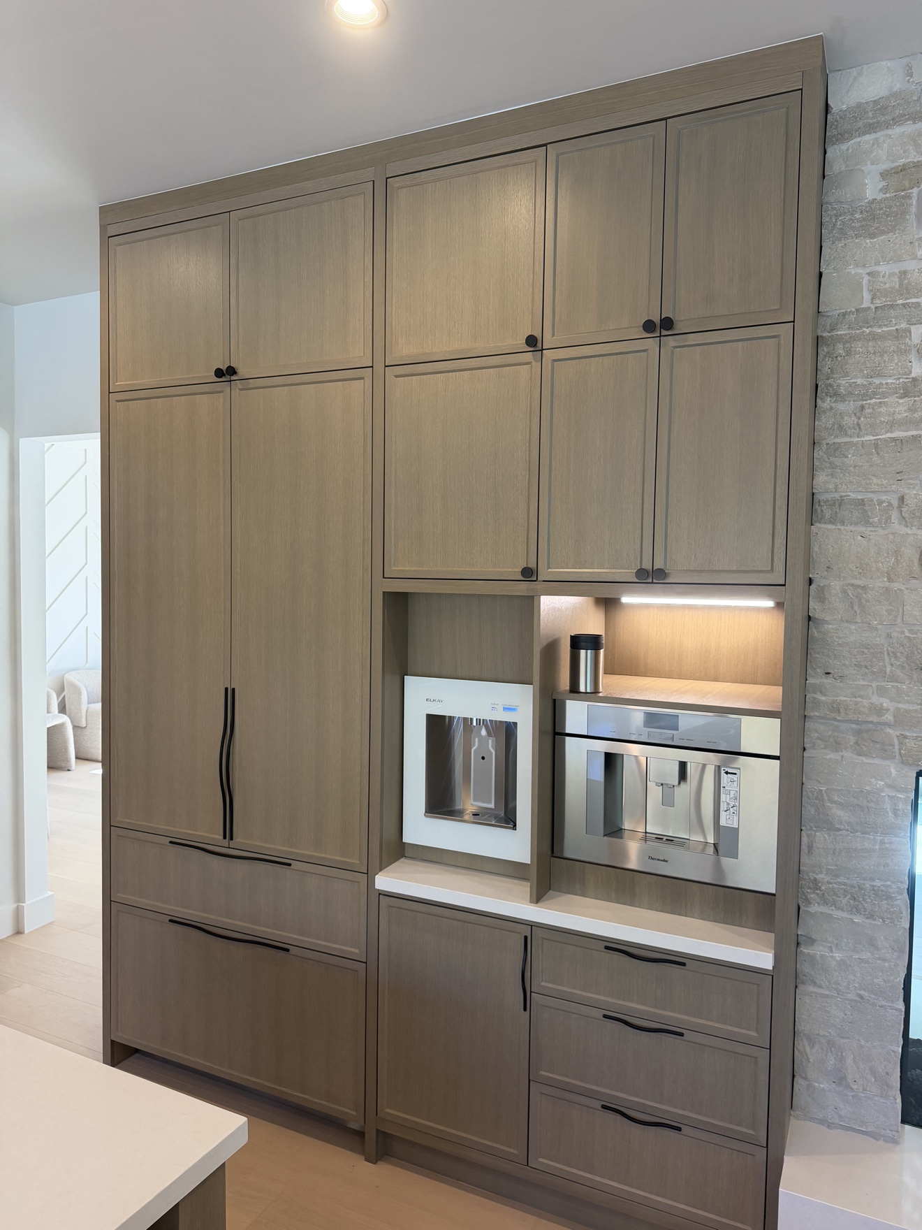 Hillsborough tall pantry wall in white oak grain with a built-in coffee machine and water dispenser niche