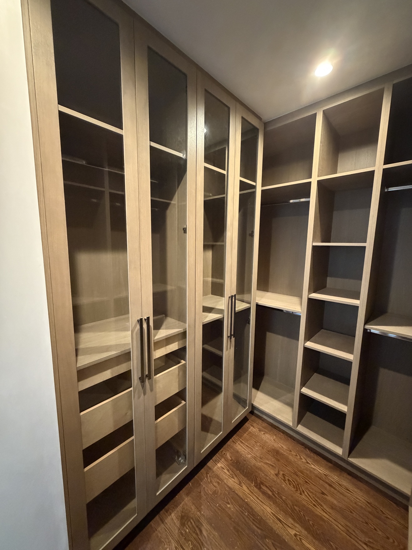 Parker walk-in closet fitted with stained white oak shelves and frameless drawers