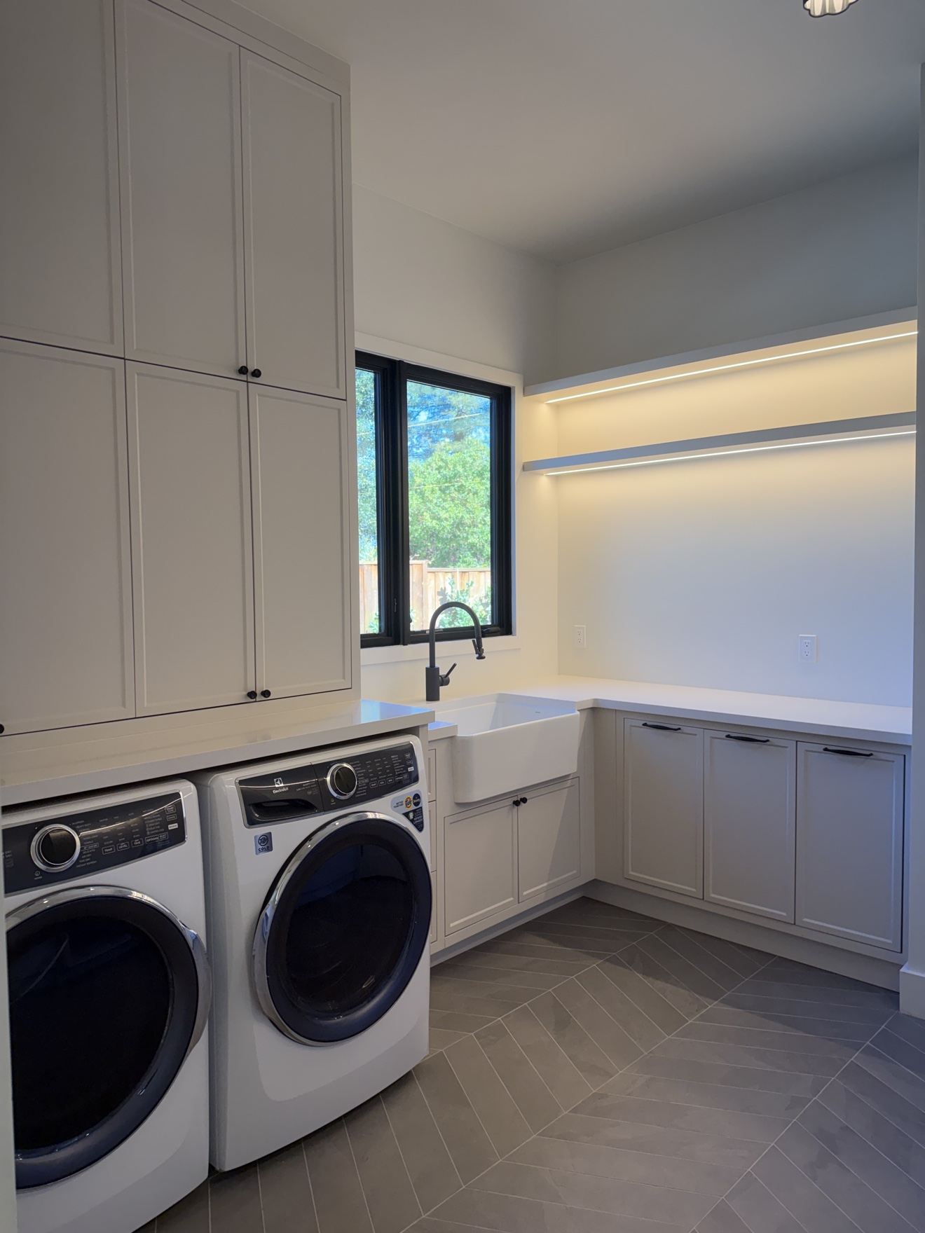 Hillsborough laundry room with tall painted cabinets, a farmhouse sink, and LED-lit open shelving