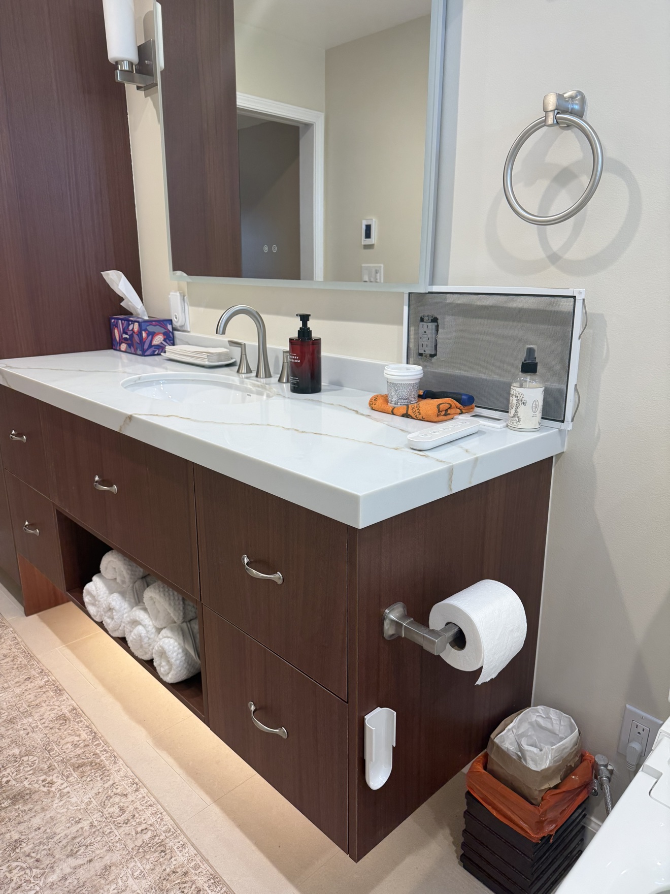 SSF deep walnut grain vanity close-up with a veined white quartz countertop, undermount sink, and open towel shelf