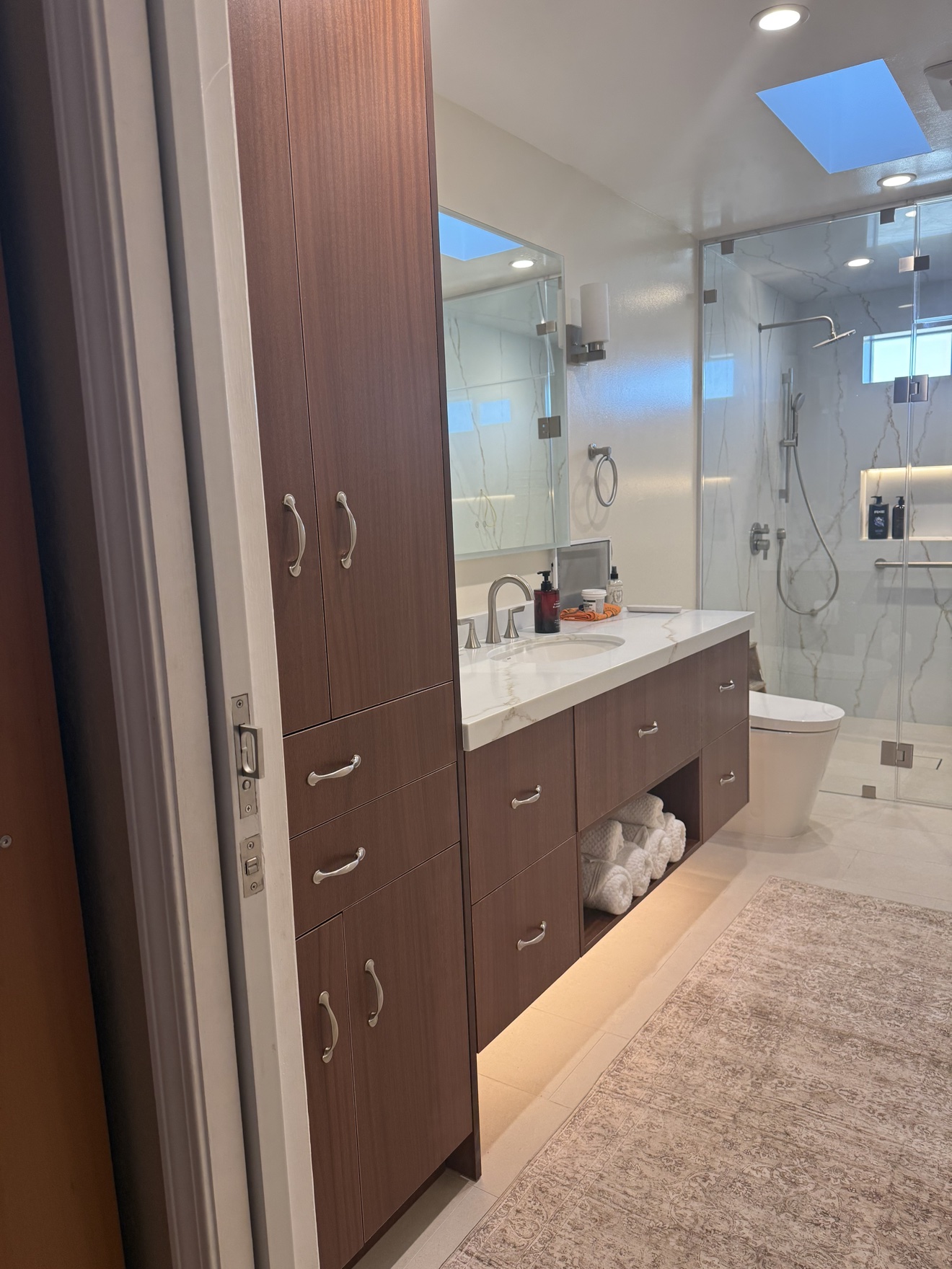 SSF bathroom wide view from the doorway showing the tall walnut tower, vanity run, and glass shower