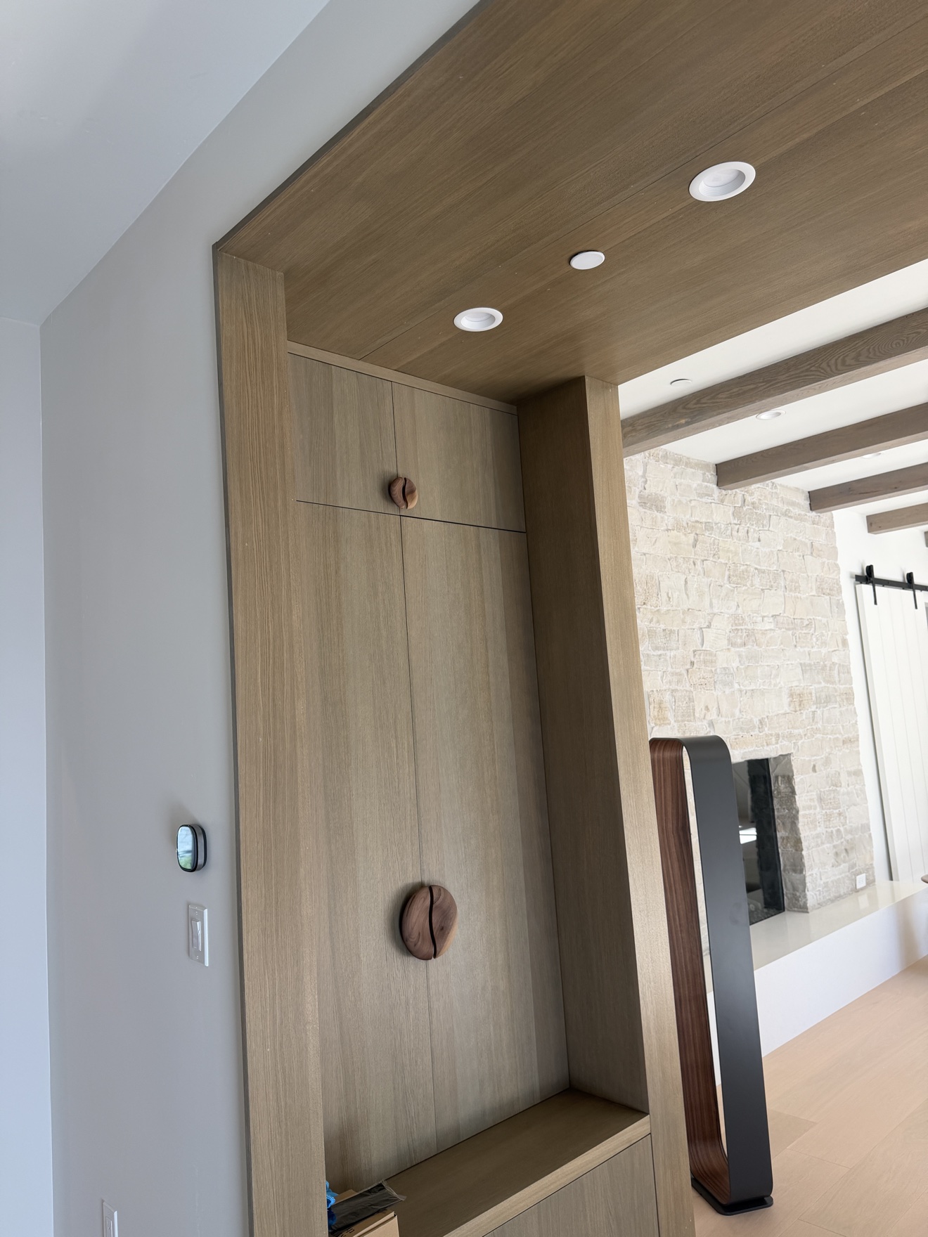 Hillsborough entry millwork in white oak grain with round walnut pulls and a wood-lined ceiling soffit