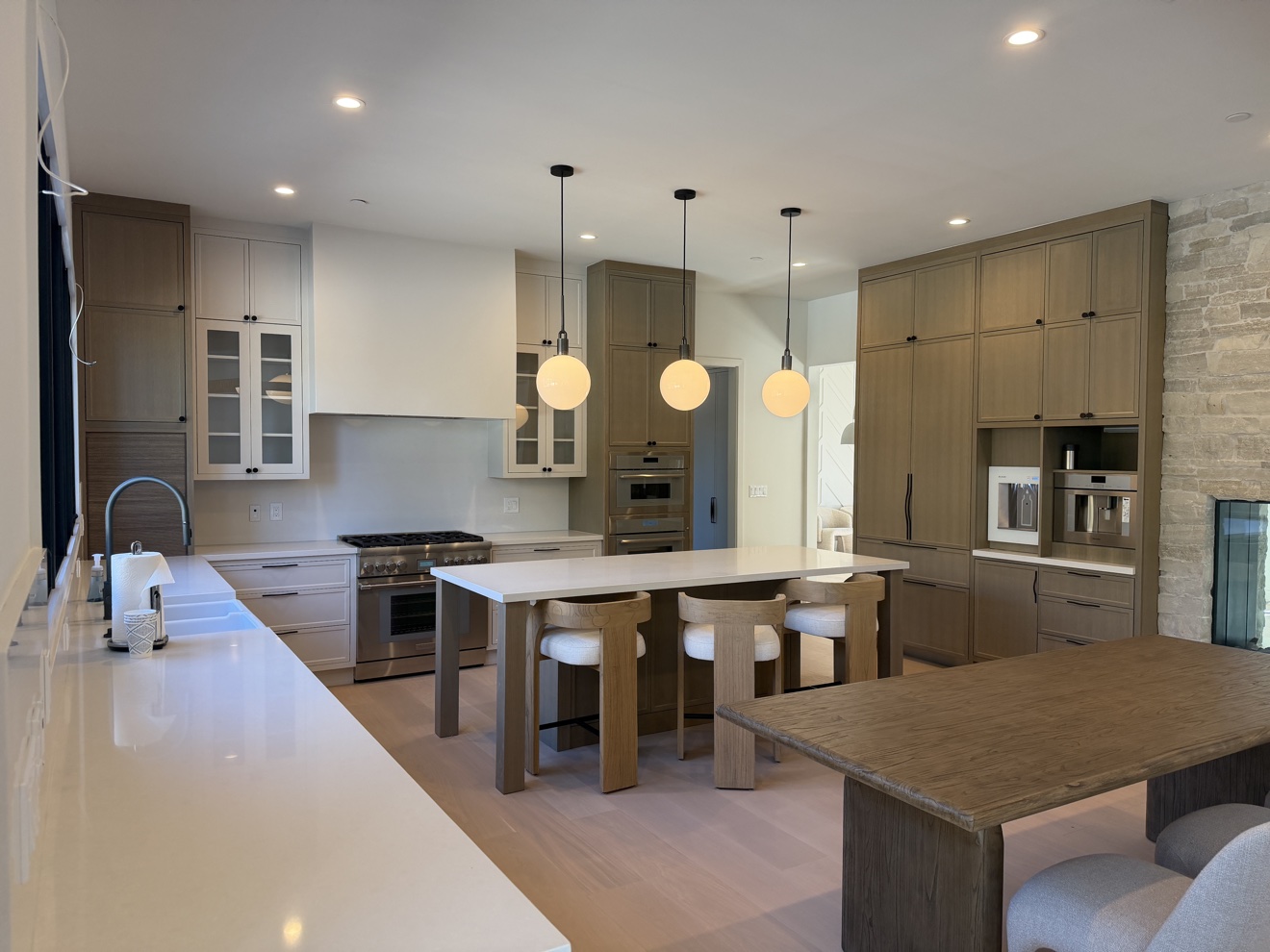 Hillsborough kitchen overview with white oak frameless cabinetry, island seating, globe pendants, and a tall coffee bar wall